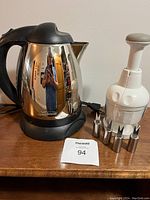Sunbeam electric kettle on base next to Pampered Chef food chopper and six stainless steel corn holders