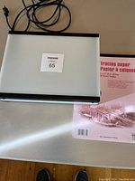 Top view of the Seerite light box with power cord and included tracing paper pad on a table.