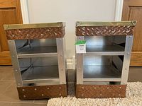 Pair of rectangular metal end tables, showing open shelving and mixed metal construction with diamond tread pattern on side panels and copper and brass accents.
