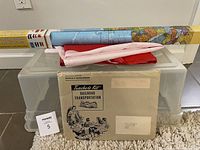 Teaching kit booklet titled 'Teacher's Kit Railroad Transportation' displayed with a large rolled-up world map box and folded Canadian flag on clear plastic storage bins.
