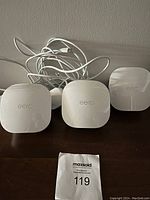 Three white eero WiFi devices and power adapters on a dark surface.
