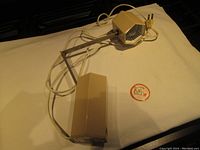 Full view of the desk lamp folded with long power cord and plug visible on beige cloth backdrop.