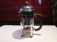 Front view of Bodum French press coffee maker with original label attached on glass carafe.