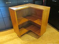 Front view of wood corner bookcase showing open L-shaped shelving space with two fixed shelves and tapered legs
