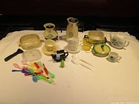 Full view of all dollhouse miniature kitchenware items laid out on a cloth