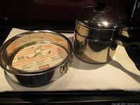 Photo of the double boiler with lid and two springform pans on a stove.