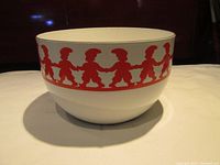 Front view of white enamel bowl featuring continuous red elf figures holding hands around the top edge.