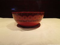 Front angle showing orange enamel bowl with black and orange floral motif around the rim.