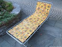 Full shot of the aluminum framed folding sun lounger with floral upholstery showing the entire length and frame condition.