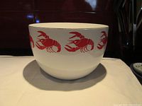 Front view of bowl showing white enamel surface and red lobster design around exterior.