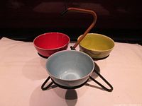 Photo showing the full condiment tray with all three ceramic dishes in red, green, and blue on white cloth background.