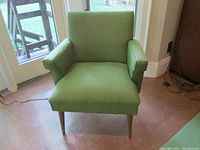 Front view of green upholstered arm chair with tapered wood legs