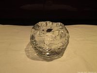Clear glass mid-century snowball style tea light holder showing textured outer surface and hollow center for candle.