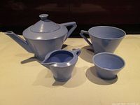 Overall view of the tea set including teapot, cup, cream jug, and sugar bowl arranged on flat surface.