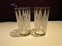 Pair of cylinder-shaped vintage clear glass juice glasses with diamond decal starburst pattern etched around sides. No chips or cracks visible.