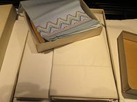 Photo showing folded vintage sheets and pillowcases, white or off-white, laid flat with visible minimal stitching detail.