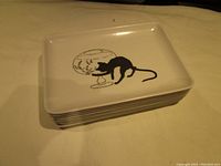 Stack of 8 rectangular melamine luncheon plates with black cat drawing on top plate.