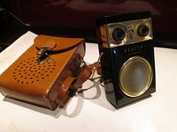 Zenith Royal 500 Deluxe portable radio next to tan leather carrying case on white surface.