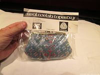 Photo of a new, sealed Welsh tapestry wool change purse packaged with a label showing brand and material information.