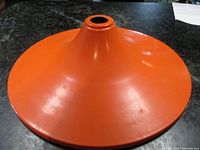 Orange enamel metal pendant light shade with a conical witch hat shape, smooth surface and central opening on top