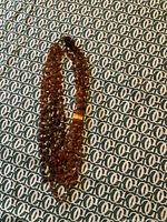 Full view of the amber multi-strand necklace laid flat, showing its shape and the clasp.