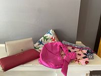 Lot contents on table showing pink Calvin Klein wallet, silver Ralph Lauren wallet, and three cosmetic bags in various colors and prints