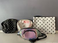 Four bags displayed: black LeSportsac cosmetic bag with gold polka dots, pink floral and striped LeSportsac bag, iridescent SkinnyDip shoulder pack, and white Kate Spade polka dot cosmetic bag