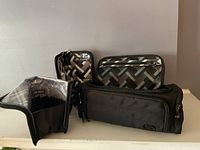 Four items shown together: mini trolley case, small square pouch, and two cosmetic brush holders with grey geometric pattern.