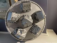 Top-down view of the metal cake pan featuring cavities shaped as village houses and a central round building with textured roofs, doors, and windows.