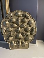Front view of NordicWare seashell-shaped mini cake pan showing detailed molds such as conch, scallop, and starfish shapes.