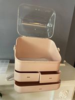 Pink rectangular organizer box with transparent lid open showing internal storage space and two front drawers closed