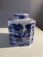 Front view of the square blue and white Spode tea caddy showing Italian pattern scenic design with trees and buildings.
