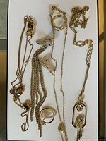 Full view of all jewelry items laid out on white surface showing earrings, rings, necklaces with bird motifs and all stones intact.