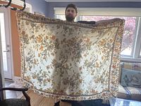 Tablecloth held up by a person showing full floral fall pattern with border design in living room setting
