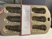 Top-down view of the cakelet pan showing six cavities shaped like parts of a steam locomotive train with William Sonoma label in center.