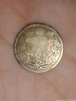 Obverse side of 1892 Canadian 25 cent coin showing maple leaf wreath design, date 1892 and some rainbow toning present on silver surface.