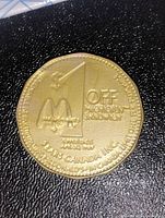 Gold-colored plastic token coin with raised text '$1 OFF McDONALD'S SANDWICH', McDonald's logo, and 'SEARS CANADA INC. Valid in Canada only.'