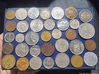 Top-down photo of 34 assorted international coins arranged in rows, showing various designs and metals.