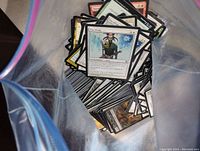 Photo of Magic The Gathering cards inside a plastic bag showing front side of some cards with artwork and text.