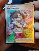 Photo showing the Marnie's Pride Full Art Holo Foil Pokemon card held in hand, highlighting holographic foil and card condition.
