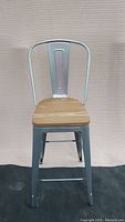 Front view of very tall steel frame bar stool with natural wood seat, showing backrest and seat design.