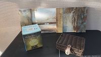 View of three items including beach scene print, rattan lamp box, and woven basket