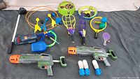 Full lot including two rocket launchers with rockets, paddle ball rackets, lawn darts, skip disc, and disco ball toy