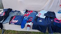 Overview of folded Washington Wizards shirts, sweatshirts, and socks laid out on a couch, showing variety of sizes and colors with team branding.