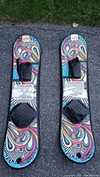Top down photo of the pair of kid's colorful snowboards showing all straps and graphics.