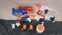 Photo showing all included Nerf SuperSoaker blasters and accessories together from top view on beige fabric surface.