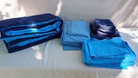 Overview of all folded bedding items including the comforter and three different blue toned sheet sets.