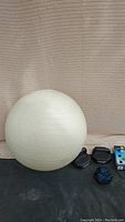 Shot showing off-white large exercise ball with ribbed surface and workout dice along with a couple of black lunge pads and a colorful dice.
