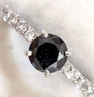 Top view showing round black diamond center and white diamond accents on band