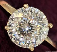 Close-up front view of the round 2ct moissanite set in 10K yellow gold band showing sparkle and prong details.